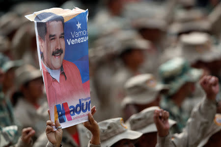 A militia member holds a banner with the image of Venezuela's President Nicolas Maduro, during a ceremony to mark the 17th anniversary of the return to power of Venezuela's late President Hugo Chavez after a coup attempt and the National Militia Day in Caracas, Venezuela April 13, 2019. REUTERS/Carlos Garcia Rawlins