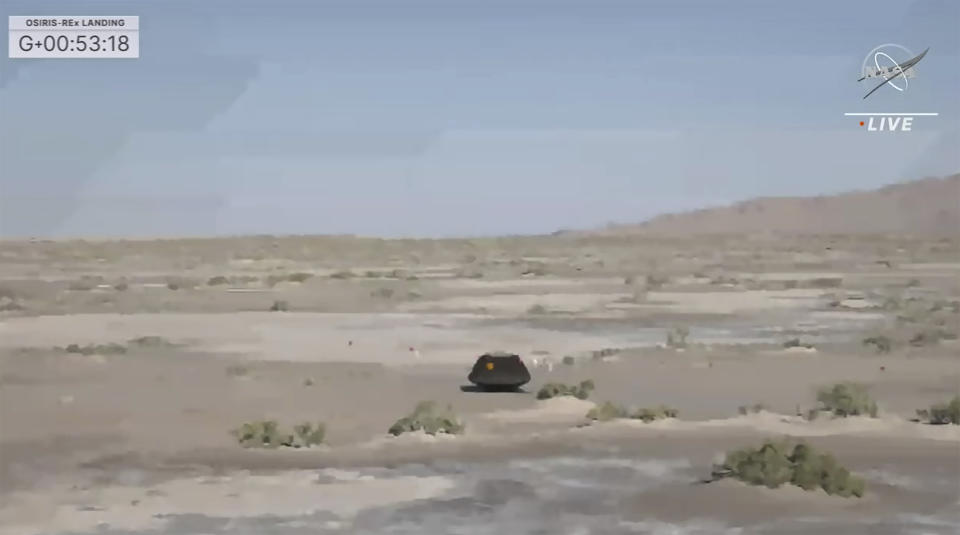 This image taken from video provided by NASA TV shows the capsule released by the Osiris-Rex spacecraft lying on the surface after landing to Earth, Sunday Sept. 24 2023. (NASA TV via AP)