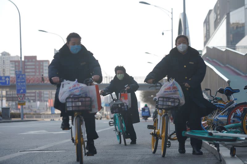 Women wearing face masks ride shared bicycles, as the country is hit by an outbreak of the novel coronavirus, in Beijing