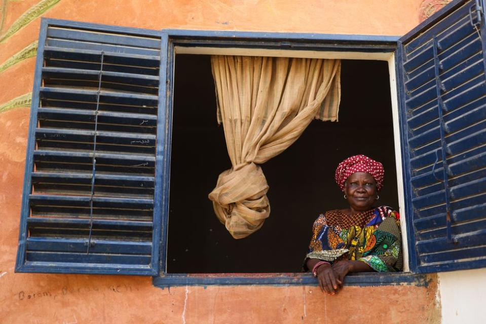 Eine Frau schaut aus dem Fenster eines Hauses.