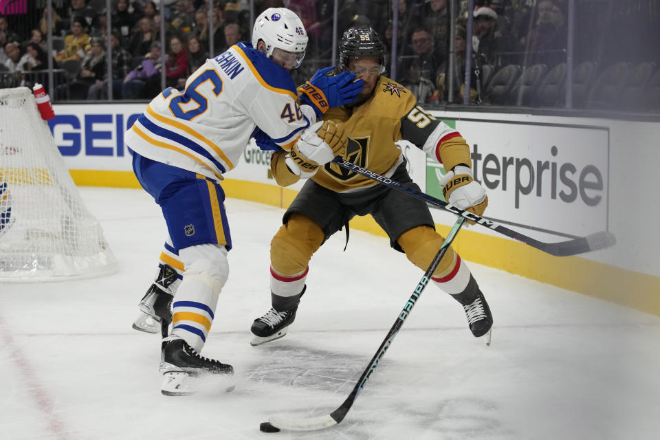 Vegas Golden Knights right wing Keegan Kolesar (55) and Buffalo Sabres defenseman Ilya Lyubushkin (46) vie for the puck during the second period of an NHL hockey game Monday, Dec. 19, 2022, in Las Vegas. (AP Photo/John Locher)