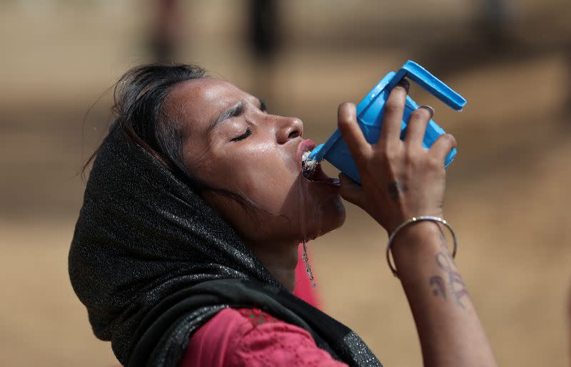 A woman drinks water from a mug on a hot summer day in New Delhi