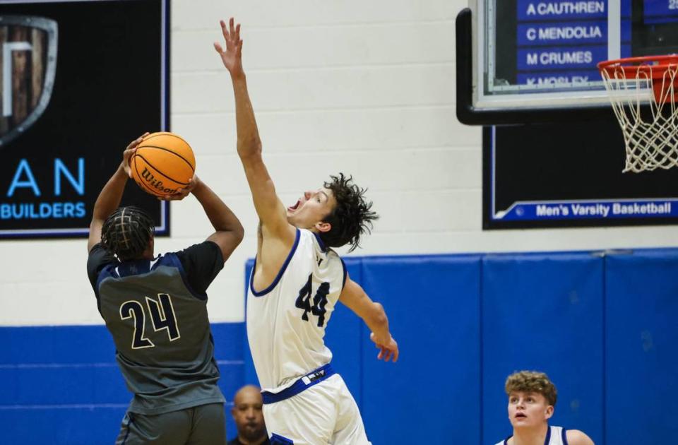 Hickory Ridge Ragin’ Bulls Travien Williams, left, shoots past a block by Lake Norman Wildcats Trent Steinour at Lake Norman High School in Mooresville, N.C., on Tuesday, February 6, 2024.
