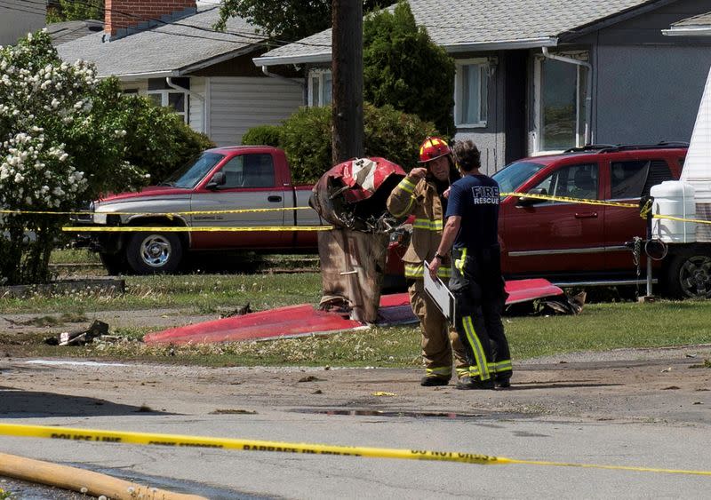 Fire officials talk in front of the tail wreckage from a Royal Canadian Air Force Snowbirds jet in Kamloops