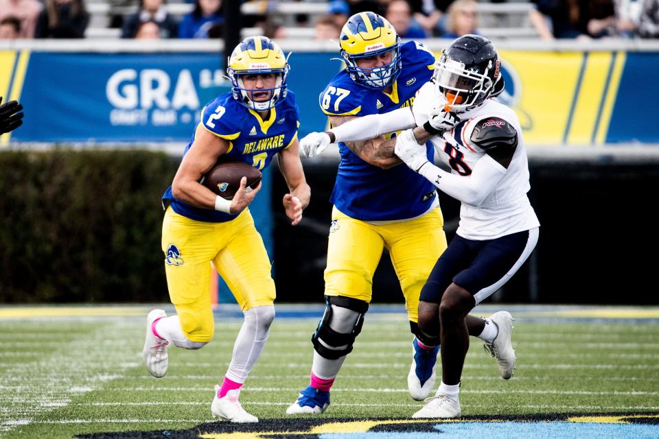 Delaware Blue Hens quarterback Nolan Henderson (2) with assistance from offensive lineman Blaise Sparks (67) runs against the sack by Morgan State Bears defensive back Jordan Johnson (8) during the homecoming football game at Delaware Stadium, Saturday, Oct. 22, 2022. Delaware won 38-7.