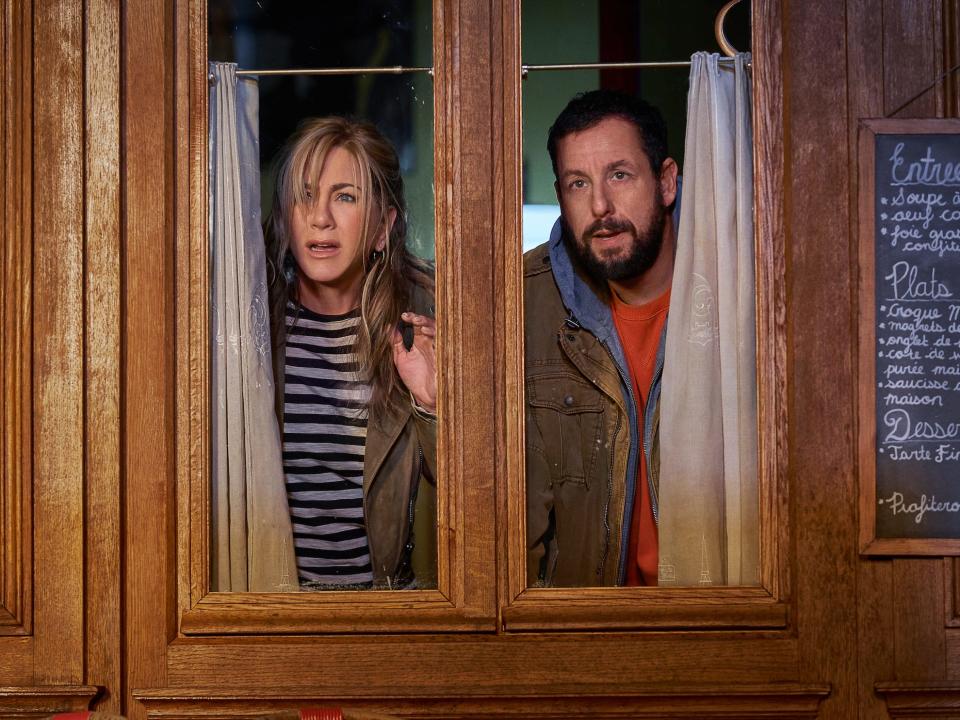 Jennifer aniston and adam sandler looking out a window in a scene from murder mystery 2