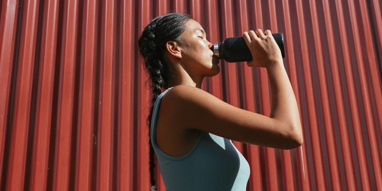 woman standing in front of the red wall and drinking water