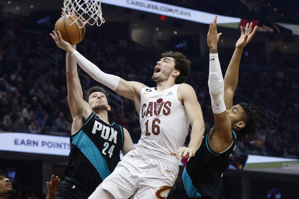 Cleveland Cavaliers forward Cedi Osman (16) shoots against Portland Trail Blazers forward Drew Eubanks (24) and forward Trendon Watford during the first half of an NBA basketball game, Wednesday, Nov. 23, 2022, in Cleveland. (AP Photo/Ron Schwane)