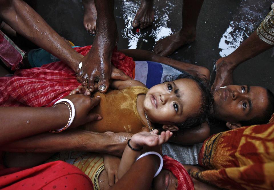 A Hindu holy man (not pictured) touches a girl with his foot as part of a ritual to bless her during a religious procession to mark the Gajan festival in Kolkata April 13, 2014. Devotees offer prayers during the month-long festival in hopes of winning the god's favour and ensuring fulfilment of their wishes. The festival ends on the last day of the Bengali calendar year, on April 15 this year. REUTERS/Rupak De Chowdhuri (INDIA - Tags: RELIGION SOCIETY TPX IMAGES OF THE DAY)