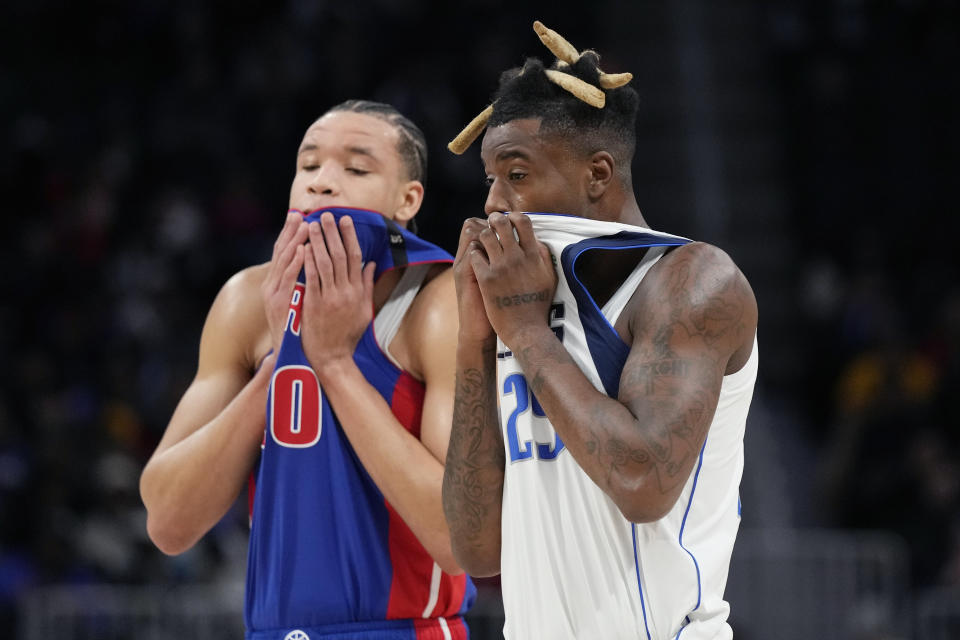 Detroit Pistons forward Kevin Knox II (20) and Dallas Mavericks forward Reggie Bullock wipe their faces during the first half of an NBA basketball game, Thursday, Dec. 1, 2022, in Detroit. (AP Photo/Carlos Osorio)