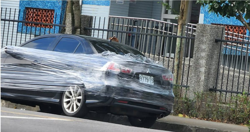 一名女網友在臉書「爆廢公社公開版」貼出一張黑色轎車被保鮮膜層層捆住的照片，引發熱議。（圖／翻攝自臉書「爆廢公社公開版」）