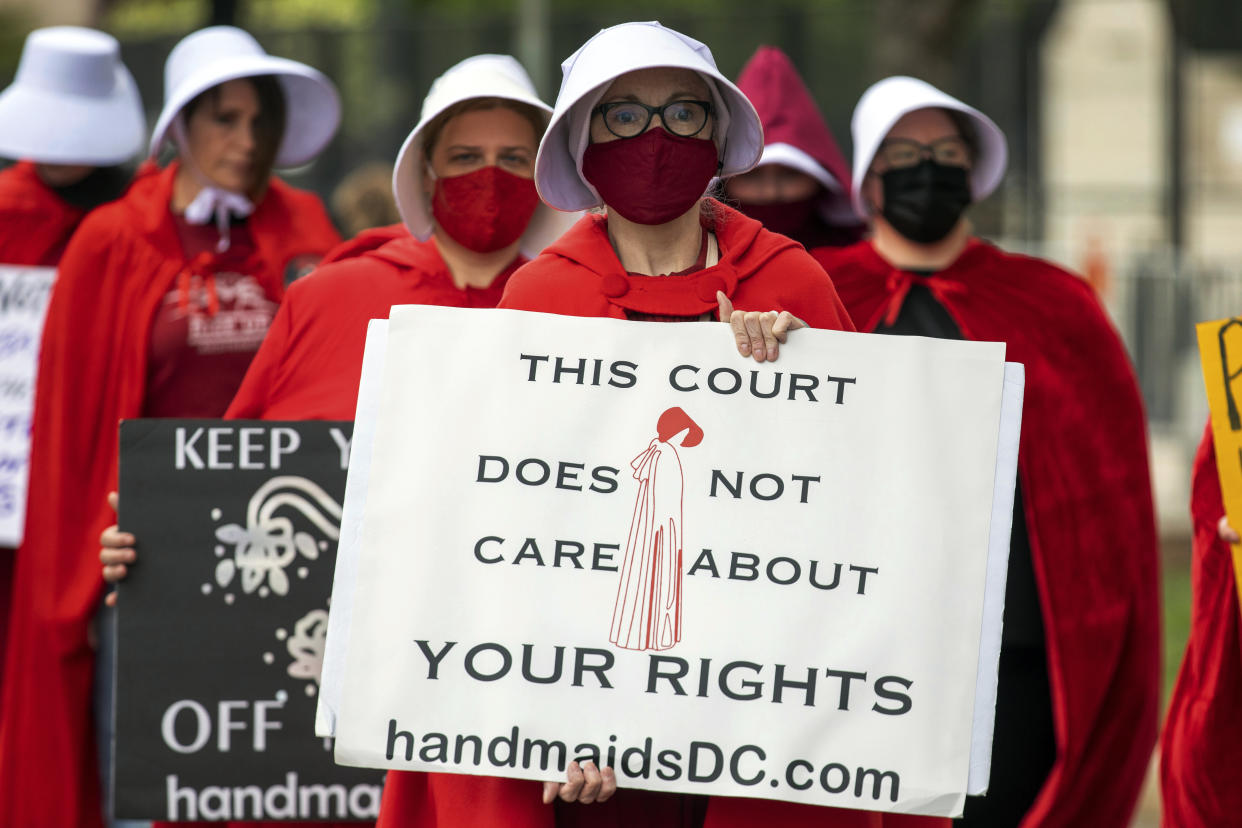 Abortion rights advocates outside the Supreme Court hold signs, one of which reads: This court does not care about your rights.