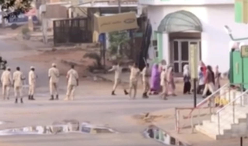 In this image made from video, Sudanese forces escort civilian in Khartoum, Sudan on Monday, June 3, 2019. Sudanese security forces moved against a protest sit-in camp in the capital Monday, witnesses and protest organizers said. Machine gun fire and explosions were heard and smoke rose from the area. Protest organizers said at least two people were killed.(AP Photo via AP video)