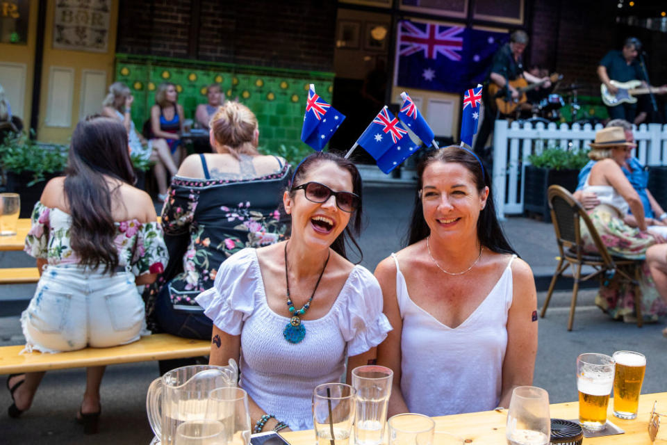 Women wearing Australian flags smile at The Mercantile Hotel in The Rocks in Sydney on Australia Day.