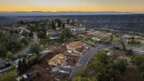 The sun sets over Valley Ridge Drive, Thursday, Oct. 26, 2023, in Paradise, Calif. Empty lots, homes under construction and residences built after the Camp Fire line the street. (AP Photo/Noah Berger)