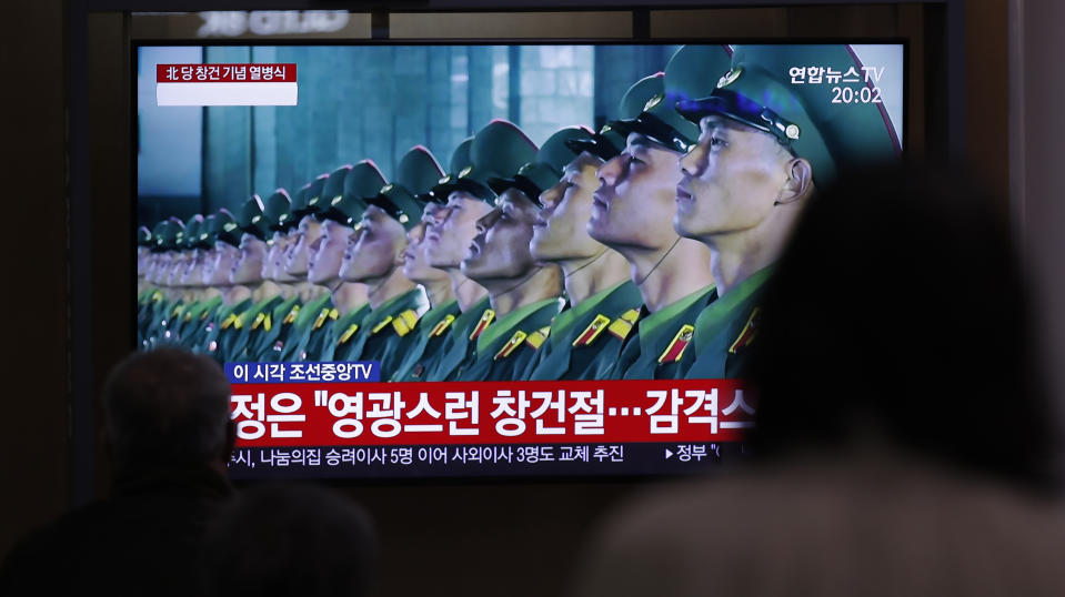 People wearing face masks watch a TV screen during a news program reporting about the ceremony to mark the 75th founding anniversary of the North Korea's ruling Workers' party, at the Seoul Railway Station in Seoul, South Korea, Saturday, Oct. 10, 2020. A part of letters read on the top "A military parade to mark the 75th founding anniversary of the North Korea's ruling Workers' party." (AP Photo/Lee Jin-man)