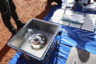 In this photo provided by the Japan Aerospace Exploration Agency (JAXA), members of JAXA retrieve a capsule dropped by Hayabusa2 in Woomera, southern Australia, Sunday, Dec. 6, 2020. A Japanese capsule carrying the first samples of asteroid subsurface shot across the night atmosphere early Sunday before successfully landing in the remote Australian Outback, completing a mission to provide clues to the origin of the solar system and life on Earth. (JAXA via AP)