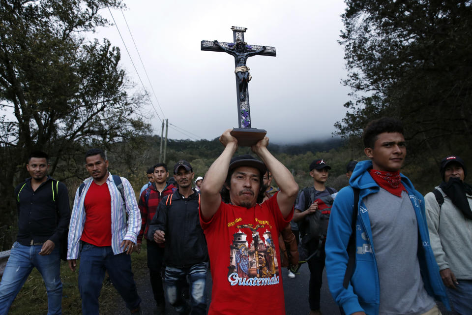 A man carries a replica of the Black Christ of Esquipulas amid Honduran migrants walking north along a road in hopes of reaching the distant United States, as they leave Esquipulas, Guatemala, just after sunrise Friday, Jan. 17, 2020. The group departed San Pedro Sula on Jan. 15. (AP Photo/Moises Castillo)