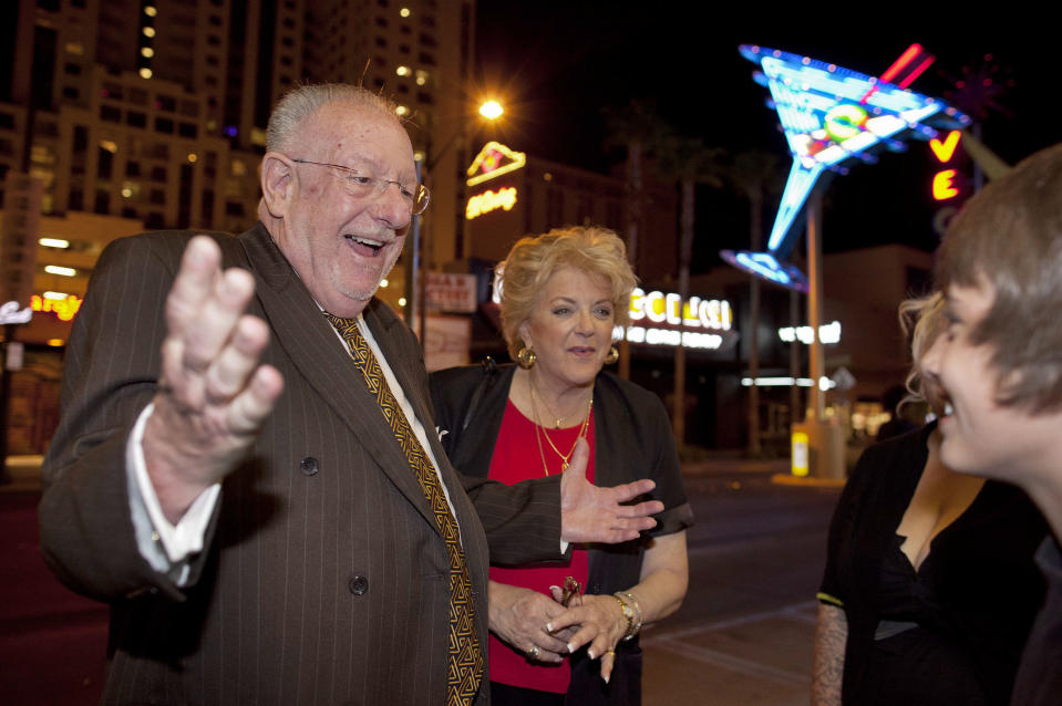 In this April 1, 2011 photo, Las Vegas mayor Oscar Goodman, left, and his wife Carolyn Goodman greet pedestrians along Fremont Street while visiting businesses during First Friday, a social block party held the first Friday of every month, in Las Vegas. The former Las Vegas mayor branded the city with a larger than life persona. And now he's branded himself again with a memoir. In “Being Oscar--From Mob Lawyer to Mayor of Las Vegas, Only in America,” Goodman tells all from his days as a lawyer representing members of the mob to his three terms as the “happiest mayor in the universe." (AP Photo/Julie Jacobson)