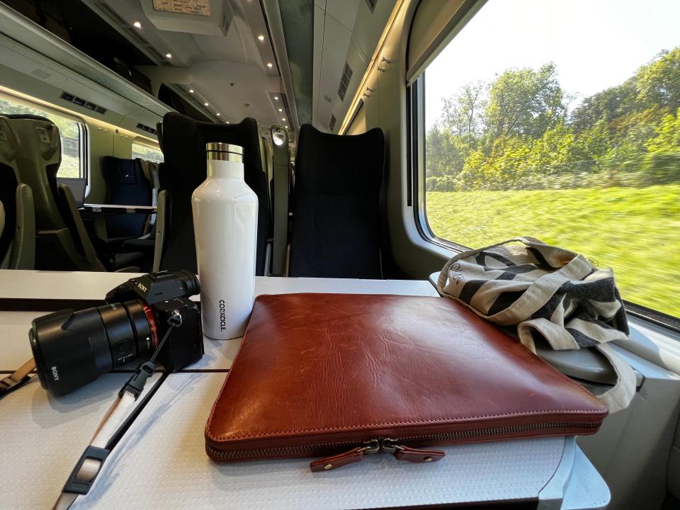 kelsey's camera, water bottle, and laptop case on a table in front of her train seat