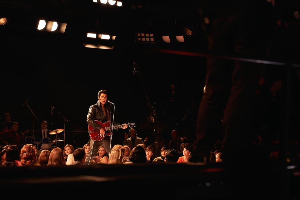 Elvis on stage in a full leather suit and red guitar about to sing