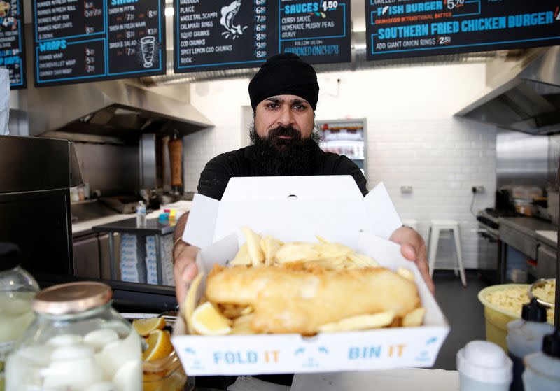 Owner of Hooked Fish and Chips shop, Bally Singh, holds a portion of fish and chips at his take-away in West Drayton