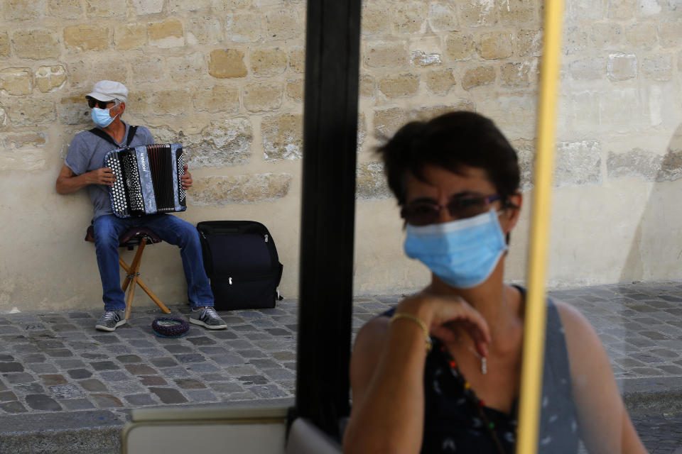 An accordionist wearing a face mask performs in the Montmartre district Monday, Aug. 10, 2020 in Paris. People are required to wear a mask outdoors starting on Monday in the most frequented areas of the French capital. The move comes as the country sees an uptick in virus infections. (AP Photo/Michel Euler