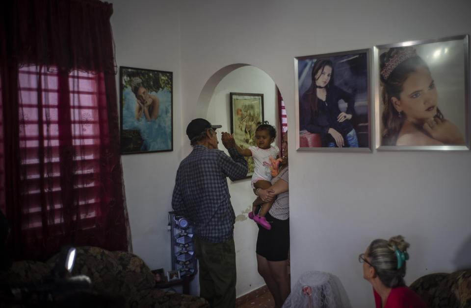 One week before 1-year-old Madisson leaves to migrate to the U.S. with her mother and aunt, Alejandro Gonzalez Lopez plays with his great-granddaughter at her home in Havana, Cuba, Tuesday, Dec. 6, 2022. It's a voyage that hundreds of thousands of Cubans have made over the last two years in a historic wave of migration. (AP Photo/Ramon Espinosa)