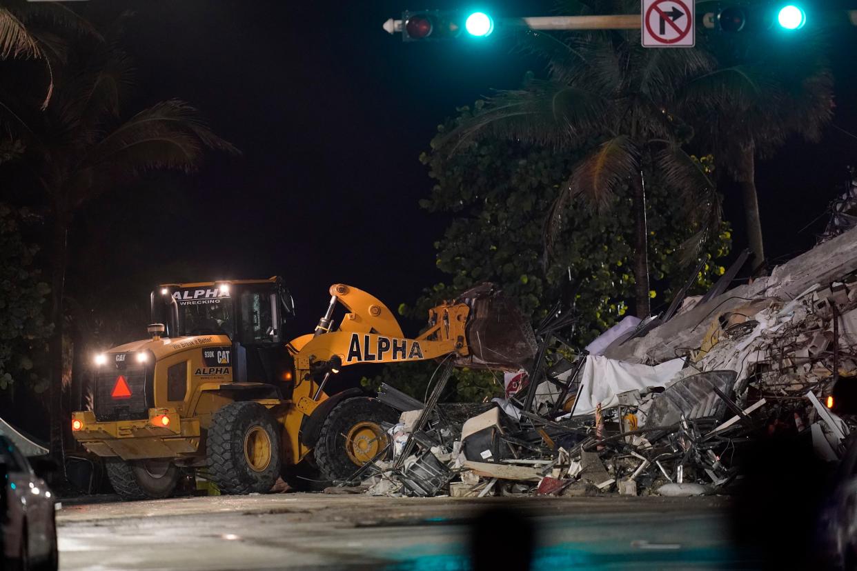 A front end loader shifts rubble mixed with furniture and household items, as rescue efforts continue where a wing of a 12-story beachfront condo building collapsed, late on Thursday, June 24, 2021, in the Surfside area of Miami.