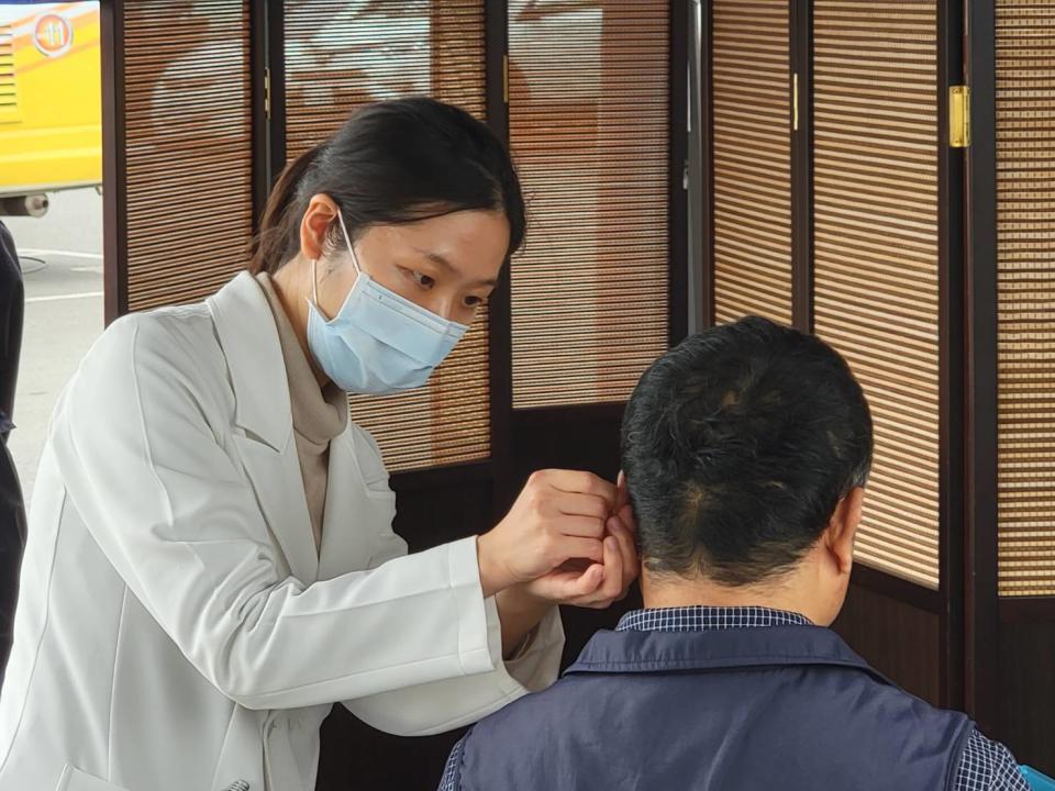 花蓮慈院中醫師蘇三華幫民眾在耳穴上貼豆，耳豆按摩可以鎮靜、舒緩情緒、安心。