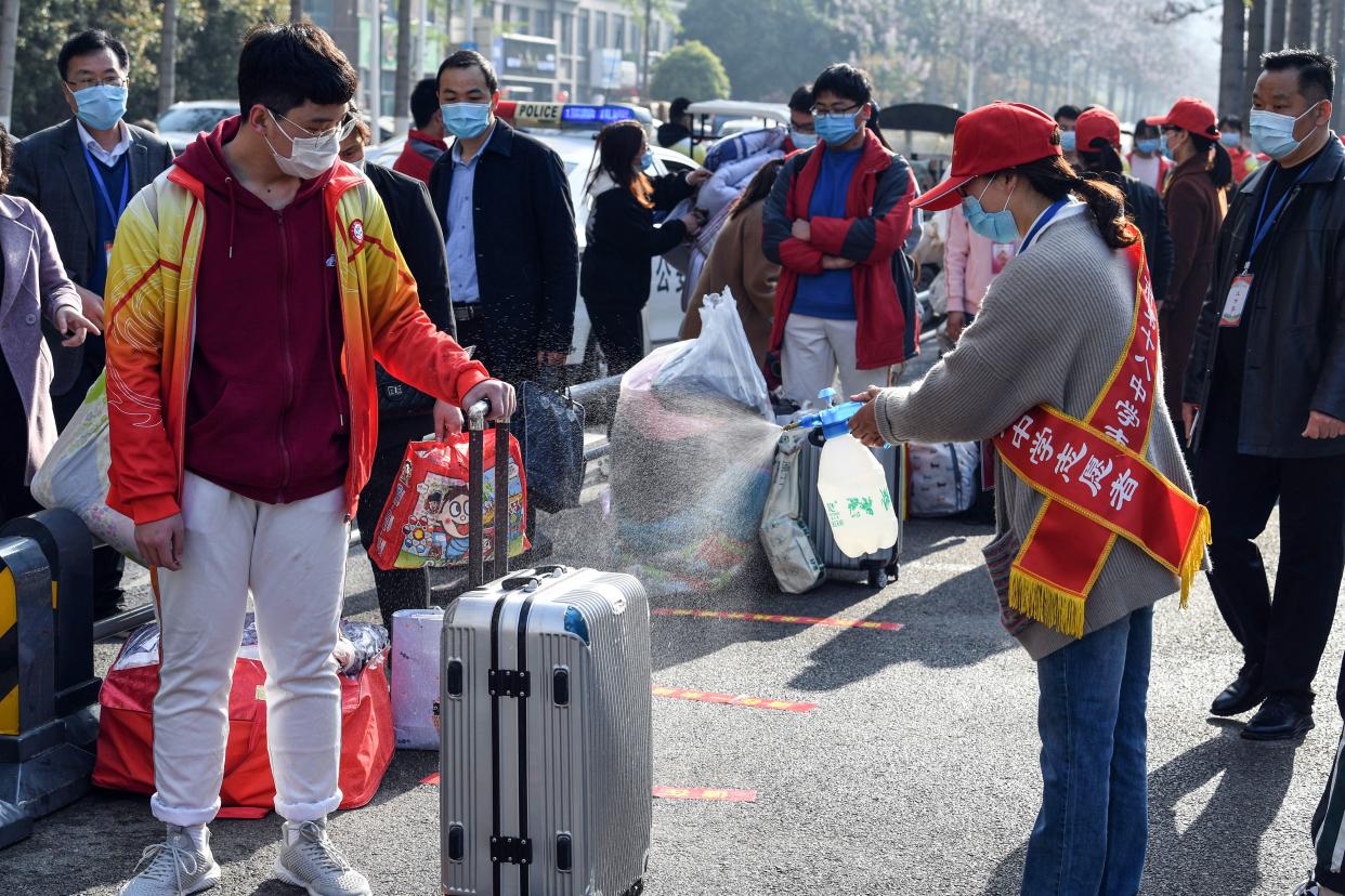 A volunteer sprays disinfectant on the luggage of a student as high school grade three students return after the term opening was delayed due to the COVID-19 coronavirus outbreak in Bozhou, in China's eastern Anhui province, on April 7, 2020.