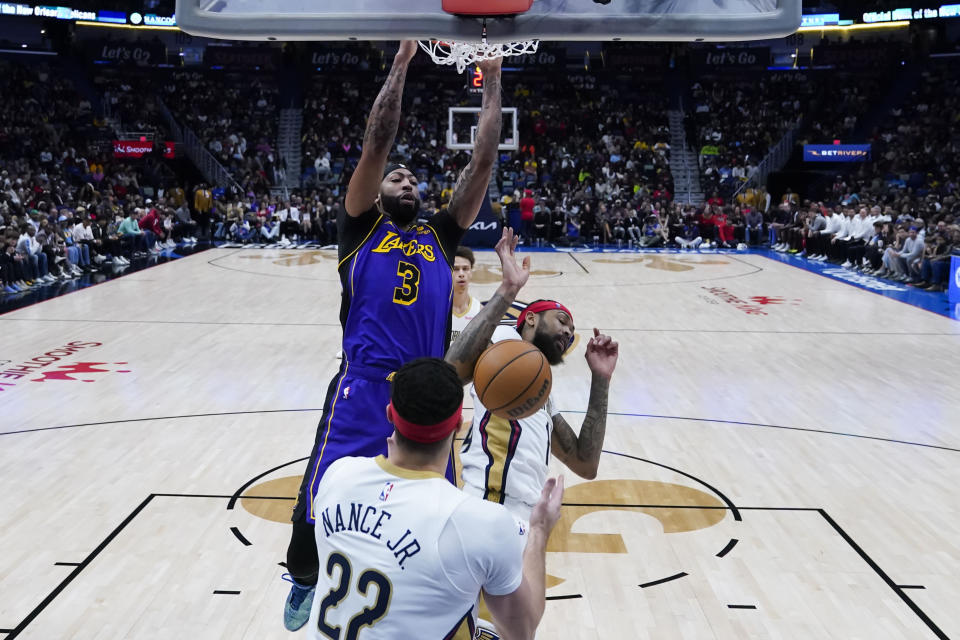 Los Angeles Lakers forward Anthony Davis (3) slam dunks over New Orleans Pelicans forward Larry Nance Jr. (22) and forward Brandon Ingram in the first half of an NBA basketball game in New Orleans, Sunday, Dec. 31, 2023. (AP Photo/Gerald Herbert)