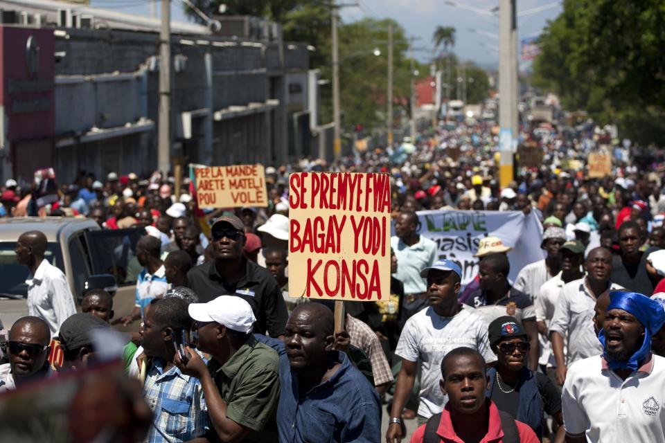 A man marches with a banner that reads in Creole; "It's the first time life is this hard," during a demonstration marking the 27th anniversary of the signing of Haiti's Constitution, in Port-au-Prince, Haiti, Saturday, March 29, 2014. Those demonstrating called for the resignation of President Michel Martelly. The protesters say Martelly hasn’t done enough to alleviate hunger since he was sworn in as president in May 2011. ( AP Photo/Dieu Nalio Chery)