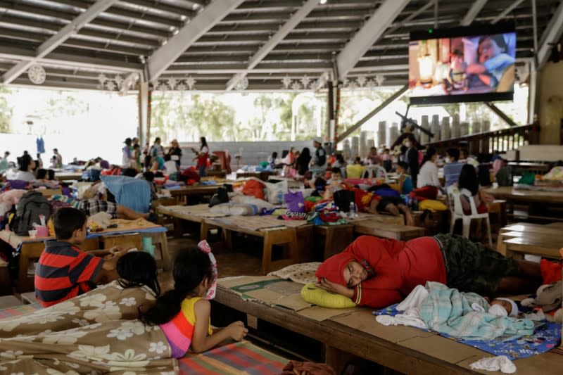 Children watch a movie from a projector screen inside a temporary evacuation center in Padre Pio Shrine for residents affected by Taal Volcano's eruption