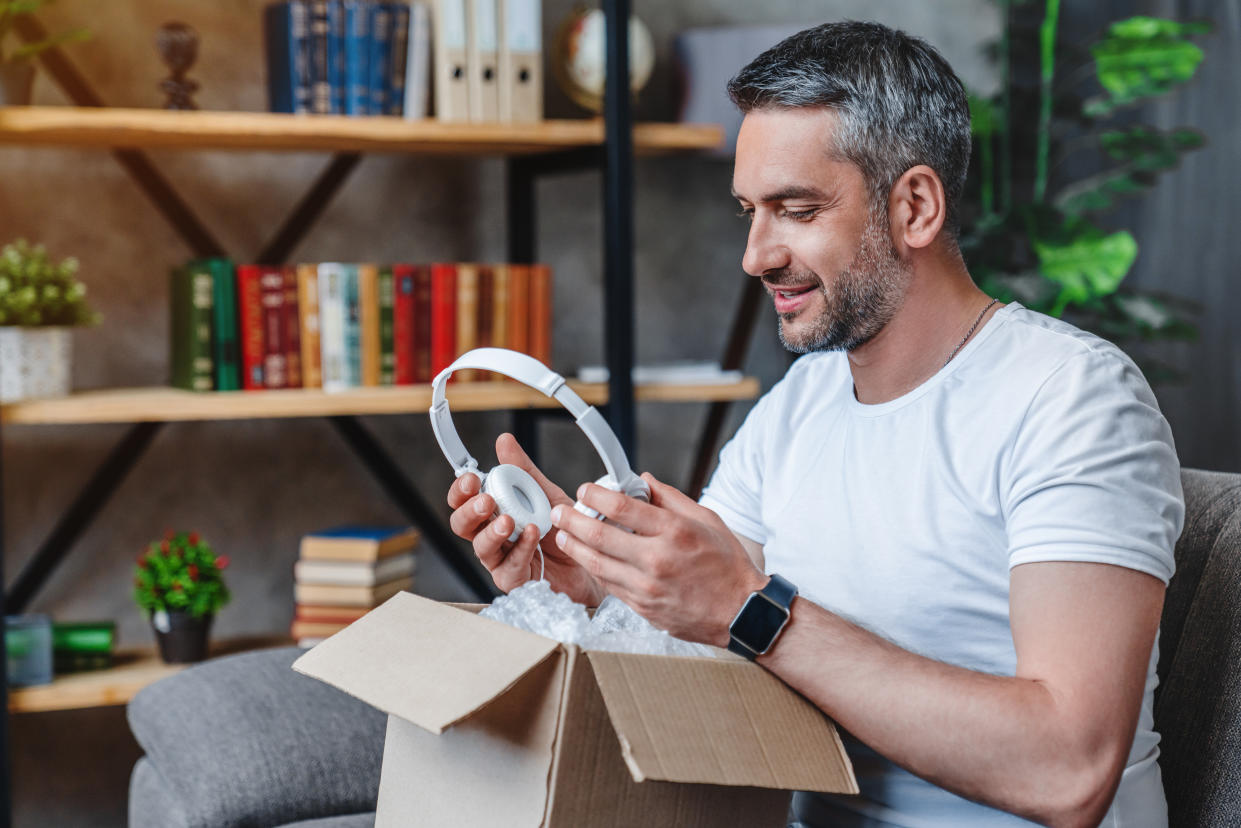 Man holding unpacking headphones from a shipping box filled with bubble wrap. 