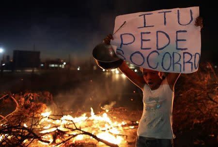 A resident of the region of Sao Paulo state that depends on the Cantareira water system, blocks a road during a protest for the eight-month rationing of water continues as a result of a record drought, in Itu, October 27, 2014. REUTERS/Nacho Doce