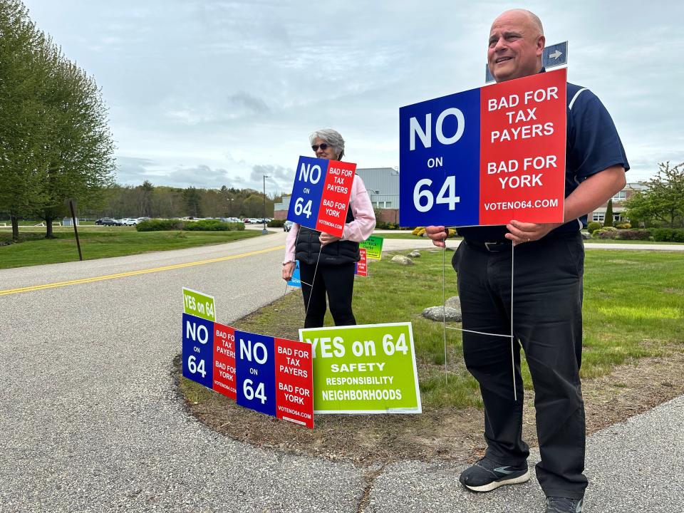 Jeanette Murphy and Mark Kinton at the polls at York High School Saturday holding signs in opposition of an article to bring regulations to short term rentals in York.