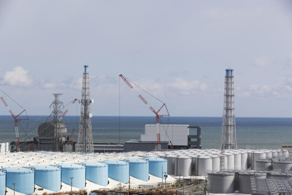 FILE - In this Feb. 27, 2021, file photo, the Pacific Ocean looks over nuclear reactor units of No. 3, left, and 4 at the Fukushima Daiichi nuclear power plant in Okuma town, Fukushima prefecture, northeastern Japan. Japan’s government adopted an interim plan Tuesday, Aug. 24, 2021 that it hopes will win support from fishermen and other concerned groups for a planned release into the sea of treated but still radioactive water from the wrecked Fukushima nuclear plant. The government decided in April to start discharging the water into the Pacific Ocean in the spring of 2023 after building a facility and compiling release plans under safety requirements set by regulators (AP Photo/Hiro Komae, File)