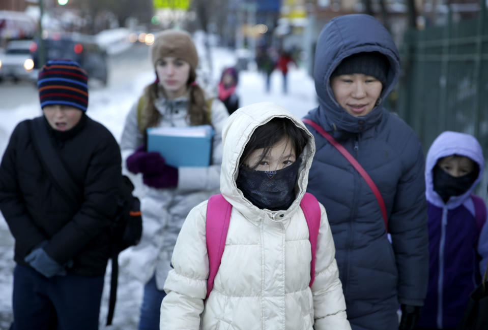 Parents and children arrive to school bundled up against the cold in the Brooklyn borough of New York, Wednesday, Jan. 22, 2014. A winter storm stretched from Kentucky to New England and hit hardest along the heavily populated Interstate 95 corridor between Philadelphia and Boston. Snow began falling at midmorning Tuesday in Philadelphia and dumped as much as 14 inches by Wednesday morning, with New York seeing almost as much. Boston and Philadelphia officials ordered schools closed Wednesday, but in New York City, the nation's largest public school system remained open. (AP Photo/Seth Wenig)