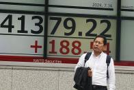 A person stands in front of an electronic stock board showing Japan's Nikkei index at a securities firm Tuesday, July 16, 2024, in Tokyo. (AP Photo/Eugene Hoshiko)