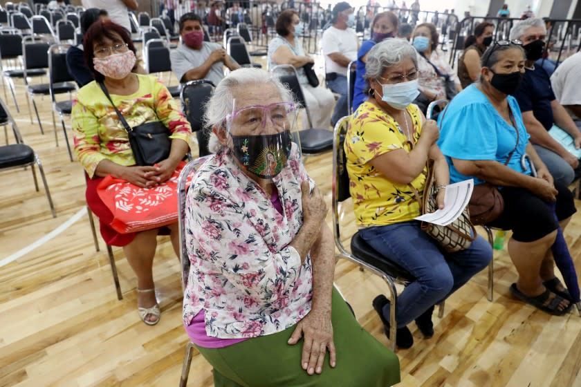 JUAREZ, NUEVO LEON - MARCH 24: Francisca Rivera Camarillo, 83, center, of Benito Juarez, who has breast cancer, puts pressure on her arm after receiving a Sinovac COVID-19 vaccine at a Mexican Government vaccination site in the Villas de San Jose neighborhood at the Polivalente Gym on Wednesday, March 24, 2021 in Juarez, Nuevo Leon. Adults over the age of 60 years were eligible to receive the vaccine. The Sinovac COVID-19 vaccine is developed by the Chinese company Sinovac Biotech. With Mexican's vaccination program lagging, wealthy Mexicans are flocking to the U.S. for COVID-19 vaccinations. Juarez is located in the eastern part of the Monterrey metropolitan area. (Gary Coronado / Los Angeles Times)