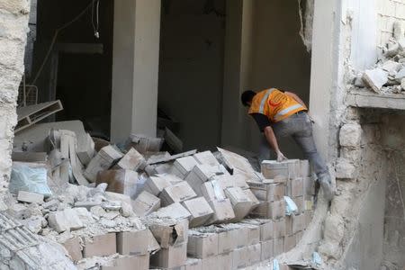 A Red Crescent aid worker jumps over medical supply boxes after an airstrike on a medical depot in the rebel-held Tariq al-Bab neighbourhood of Aleppo, Syria April 30, 2016. REUTERS/Abdalrhman Ismail