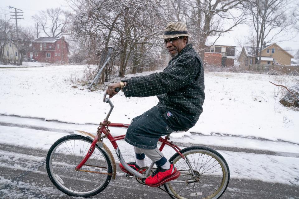 A man wearing a fedora rides his bike down a snowy Terry Street in Detroit on Wednesday, Jan. 25, 2023.