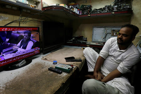 A technician looks at a screen displaying the cricket star-turned-politician Imran Khan, chairman of Pakistan Tehreek-e-Insaf (PTI) ahead of vote to elect prime minister in National Assembly, at a shop along a market in Karachi, Pakistan August 17, 2018. REUTERS/Akhtar Soomro