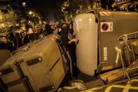 Demonstrators take shelter behind a barricade during clashes with police in Barcelona, Spain, Wednesday, Oct. 16, 2019. Spain's government said Wednesday it would do whatever it takes to stamp out violence in Catalonia, where clashes between regional independence supporters and police have injured more than 200 people in two days. (AP Photo/Bernat Armangue)