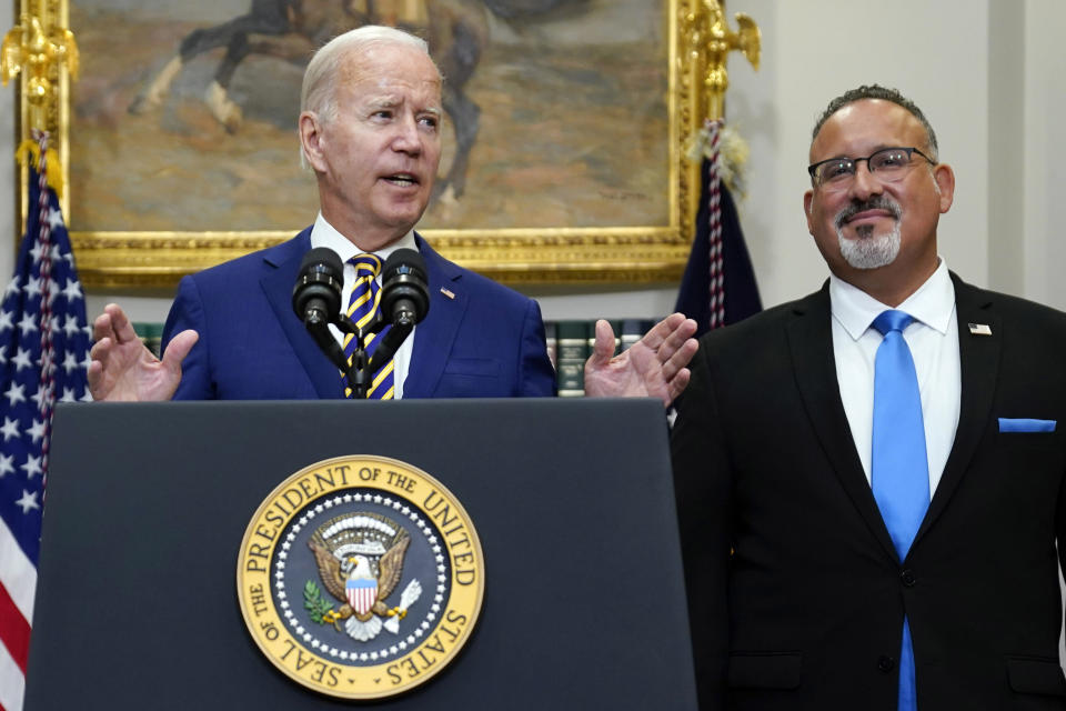 FILE — President Joe Biden speaks about student loan debt forgiveness in the Roosevelt Room of the White House, Aug. 24, 2022, in Washington. Education Secretary Miguel Cardona listens at right. Many have cheered President Joe Biden's proposal to provide student loan forgiveness to millions of Americans as a significant step toward addressing the nation's racial wealth gap and other inequities facing borrowers of color. (AP Photo/Evan Vucci, File)