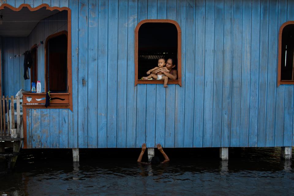 A woman holds her nephew in a house with water surrounding it