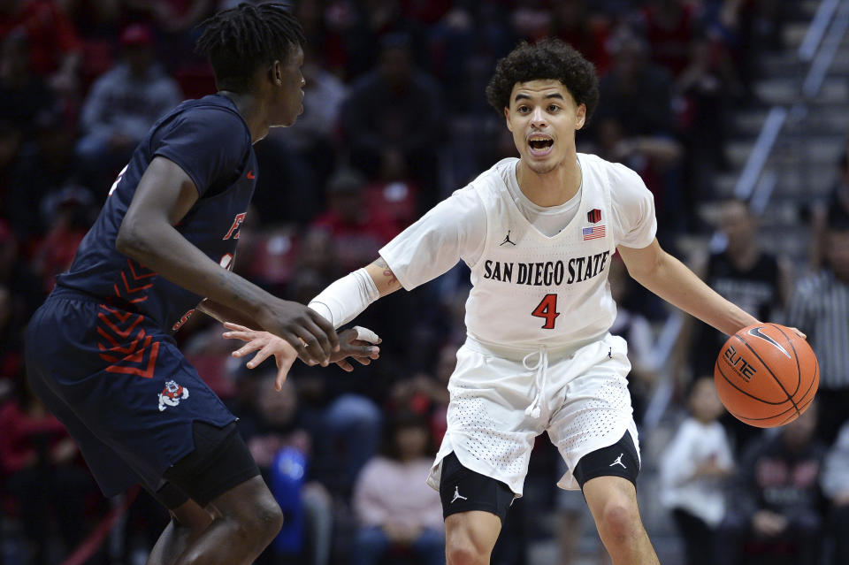 San Diego State guard Trey Pulliam (4) dribbles the ball while defended by Fresno State guard Aguir Agau (13) during the second half of an NCAA college basketball game Wednesday, Jan. 1, 2020, in San Diego. San Diego won 61-52. (AP Photo/Orlando Ramirez)