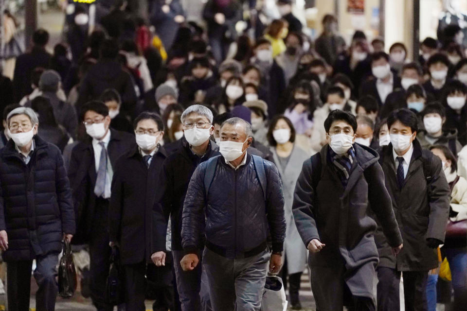 People wearing face masks to protect against the coronavirus make their way toward a station in Tokyo Monday, Dec. 21, 2020. Daily coronavirus cases have been steadily on the rise nationwide. Tokyo Gov. Yuriko Koike on Monday asked all residents to celebrate Christmas and New Year at home just with their families, and asked organizers to light-up events to close early in the night. (Kenzaburo Fukuhara/Kyodo News via AP)