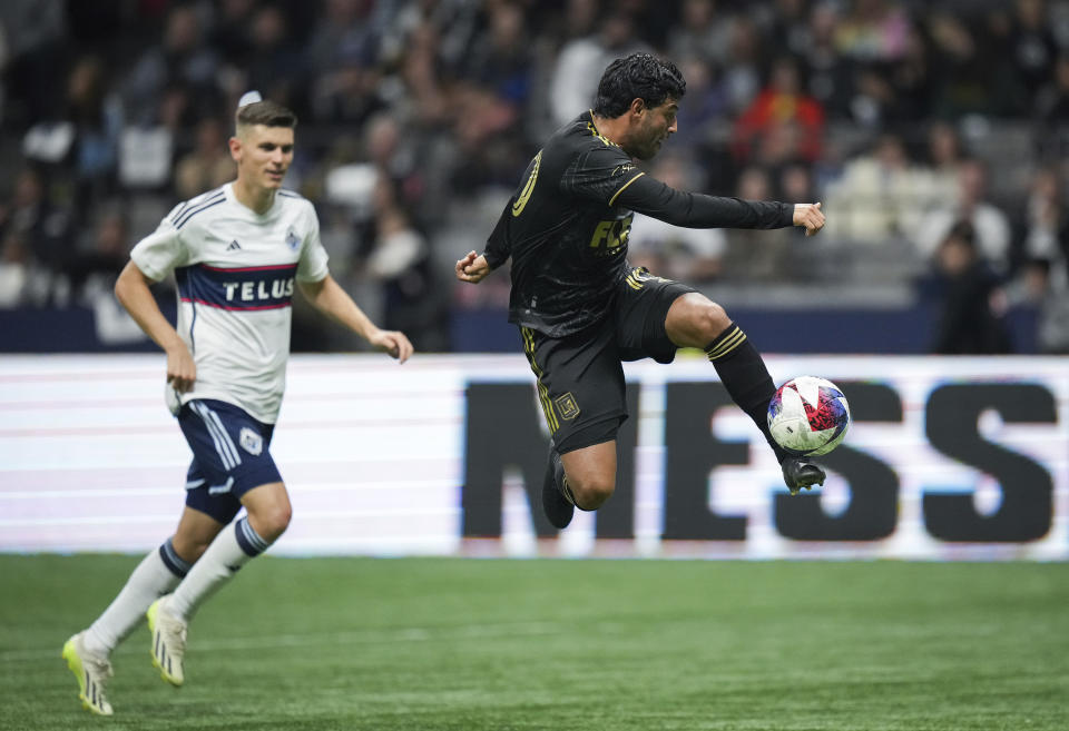 Los Angeles FC's Carlos Vela, right, takes a shot on goal as Vancouver Whitecaps' Ranko Veselinovic watches during the first half of an MLS soccer match, in Vancouver, British Columbia, Saturday, Oct. 21, 2023. (Darryl Dyck/The Canadian Press via AP)